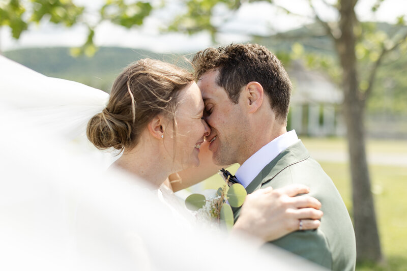 Bride and groom smile at each other as veil fills in the background behind them