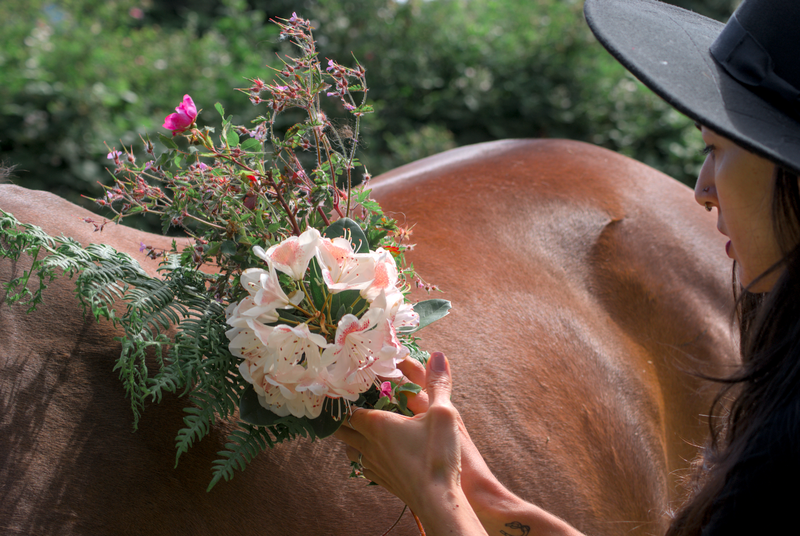 Animal Communicator holding a bouquet of flowers beside her horse. 
