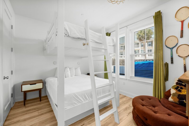 Cozy bedroom with full-size bunk beds, vintage chair and window views, perfect for families visiting 30A and Panama City Beach