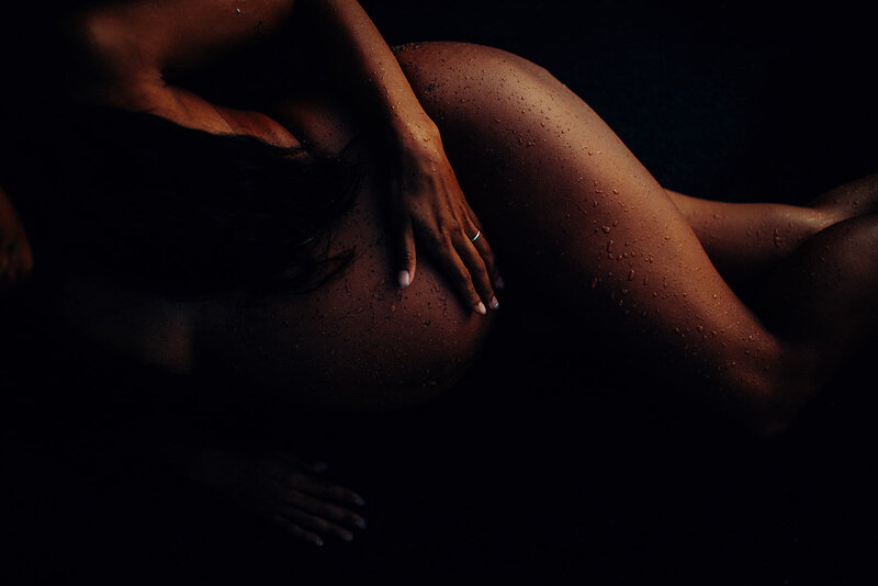 very artistic close up maternity portrait with pregnant woman with goosebumps laying on black sand on maui