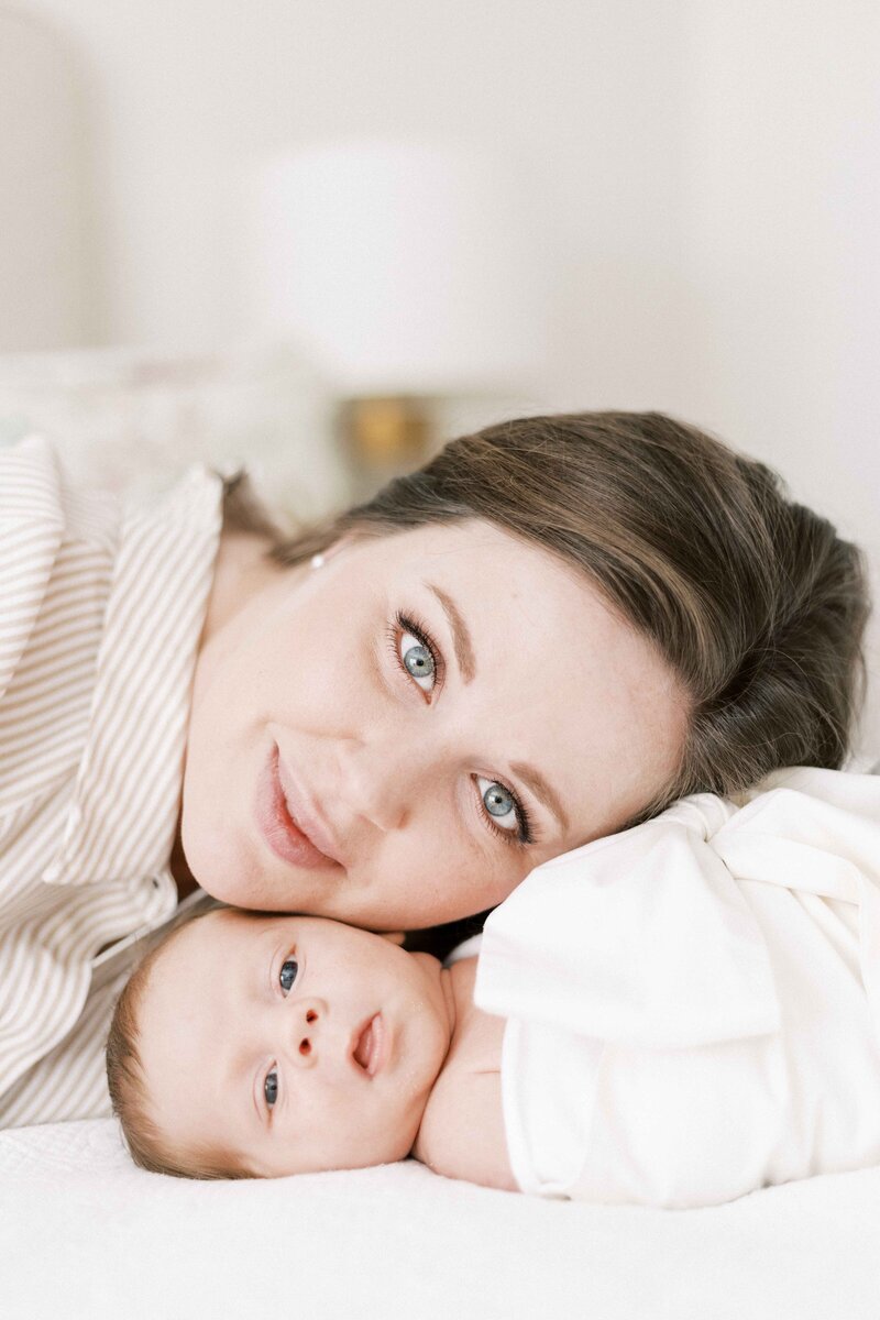mom and baby laying cheek to cheek during in-home newborn photos in peoria, illinois
