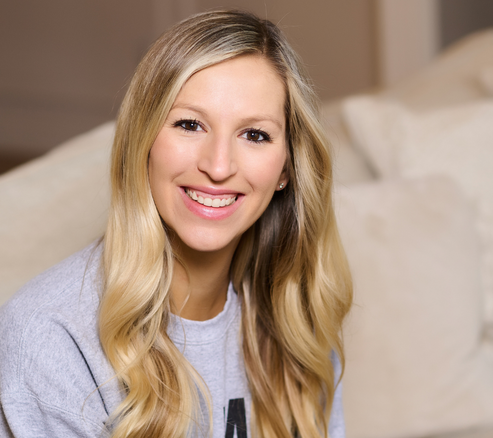 blonde woman sitting on a couch smiling