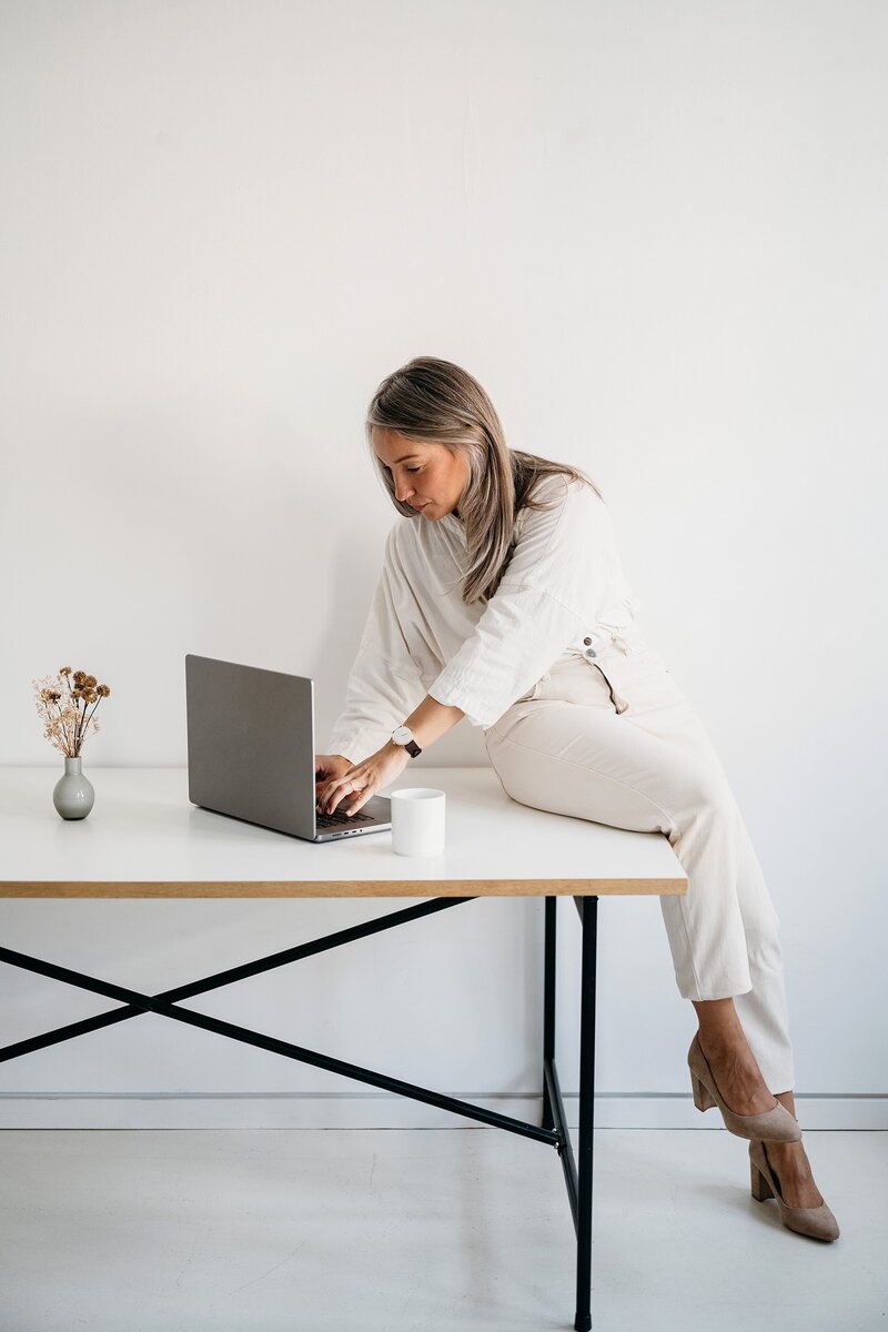 A woman sitting at the table typing on a laptop