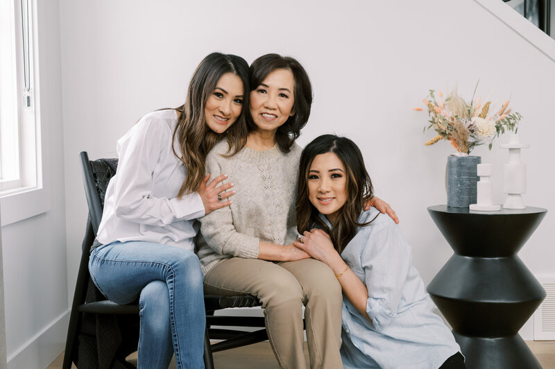 Mother sitting in the middle with daughter on each side posing for photo