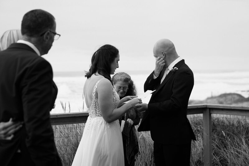 A couple stands in tall green grass against a blue sky during their Oregon Coast elopement. 