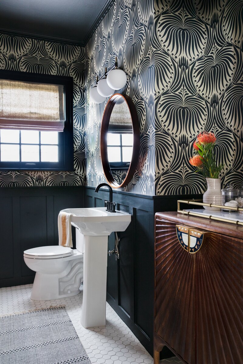 Bold Bathroom design with retro cabinetry, a freestanding sink, and textured wallpaper above dark blue wainscot panels