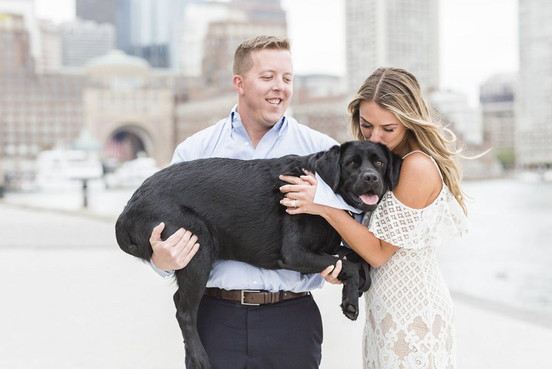 Couple holding black lab wearing a scarf