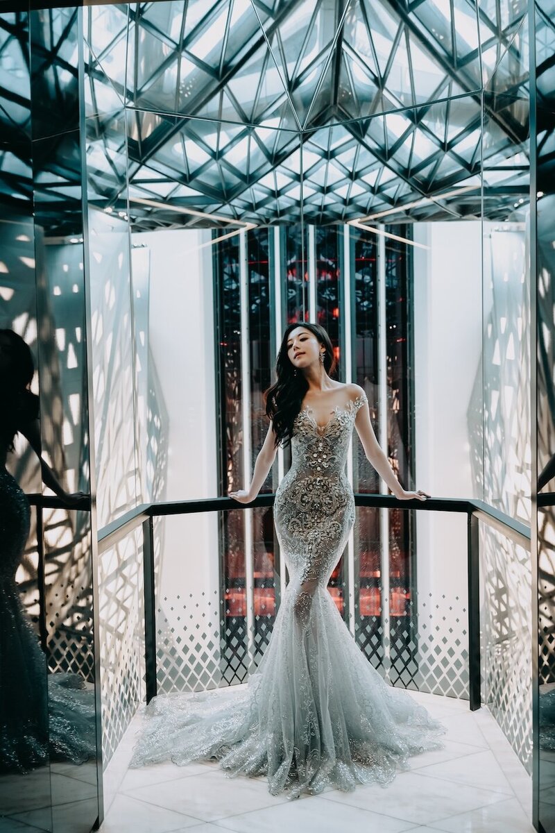 A woman in an abstract geometric lit room wearing a stunning couture dress.