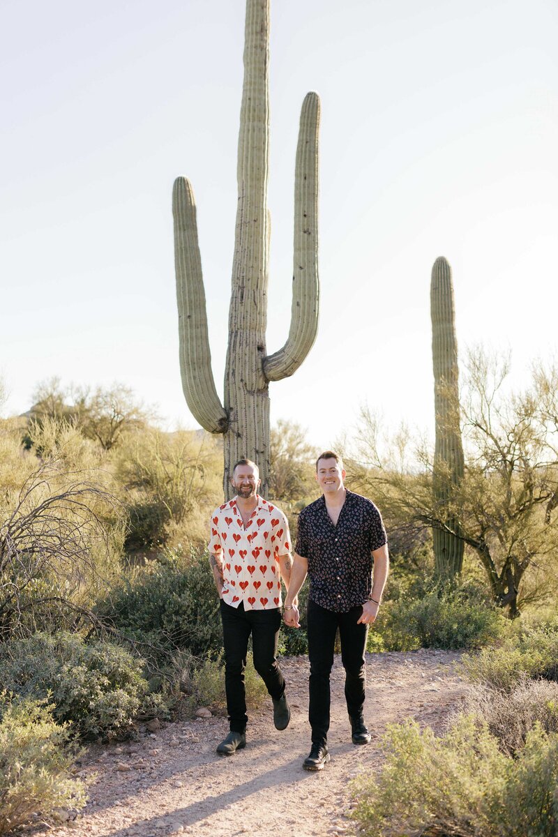 LGBTQ+ couple walk hand in hand through the Phoenix desert.