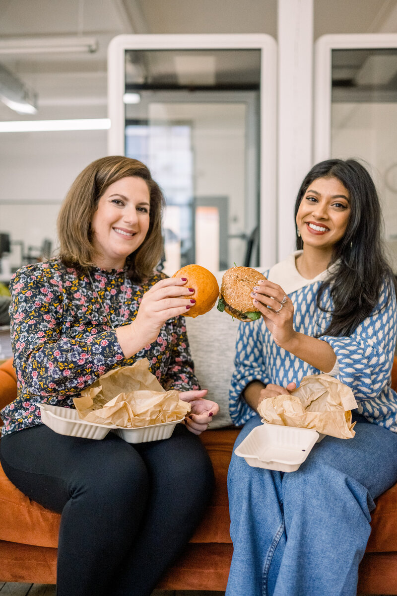 Two people holding burgers and smiling