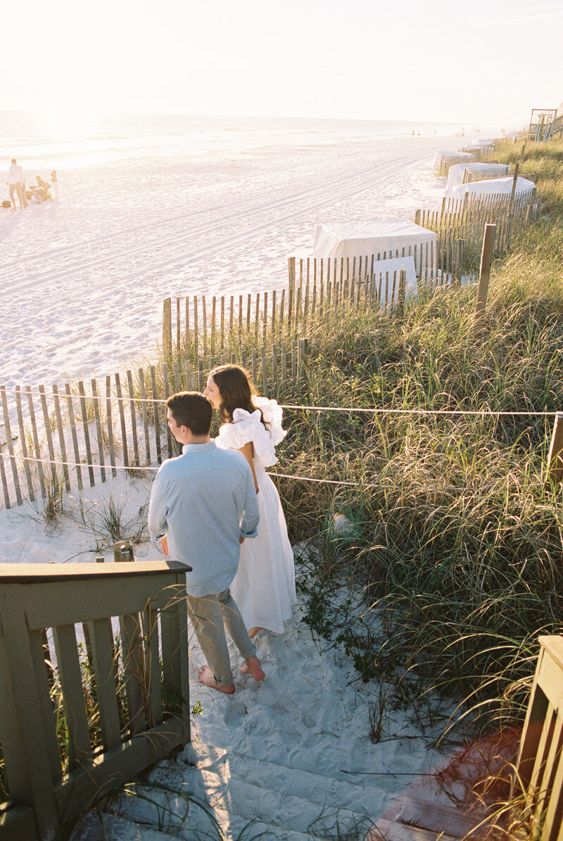 Couple walking down wooden steps to the sand at the beach