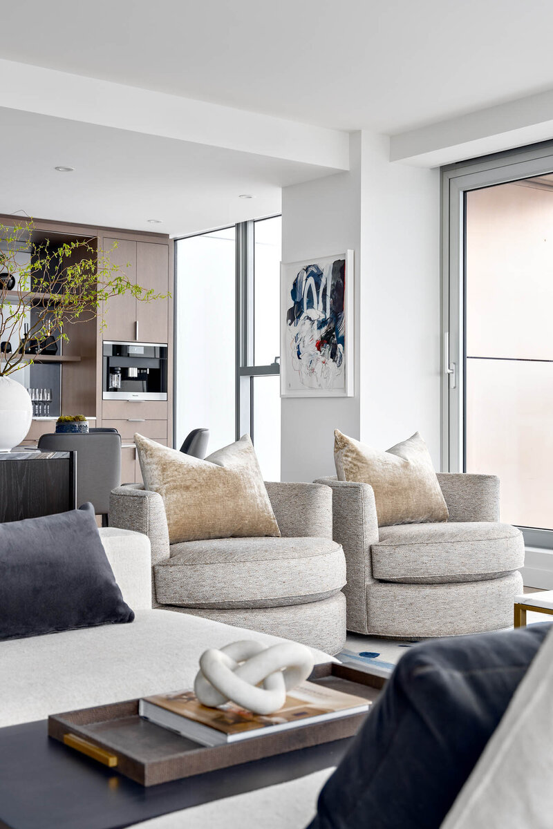 Vancouver House project, a bright and airy living room, the camera is focusing on two identical light heather grey, round, lounge chairs