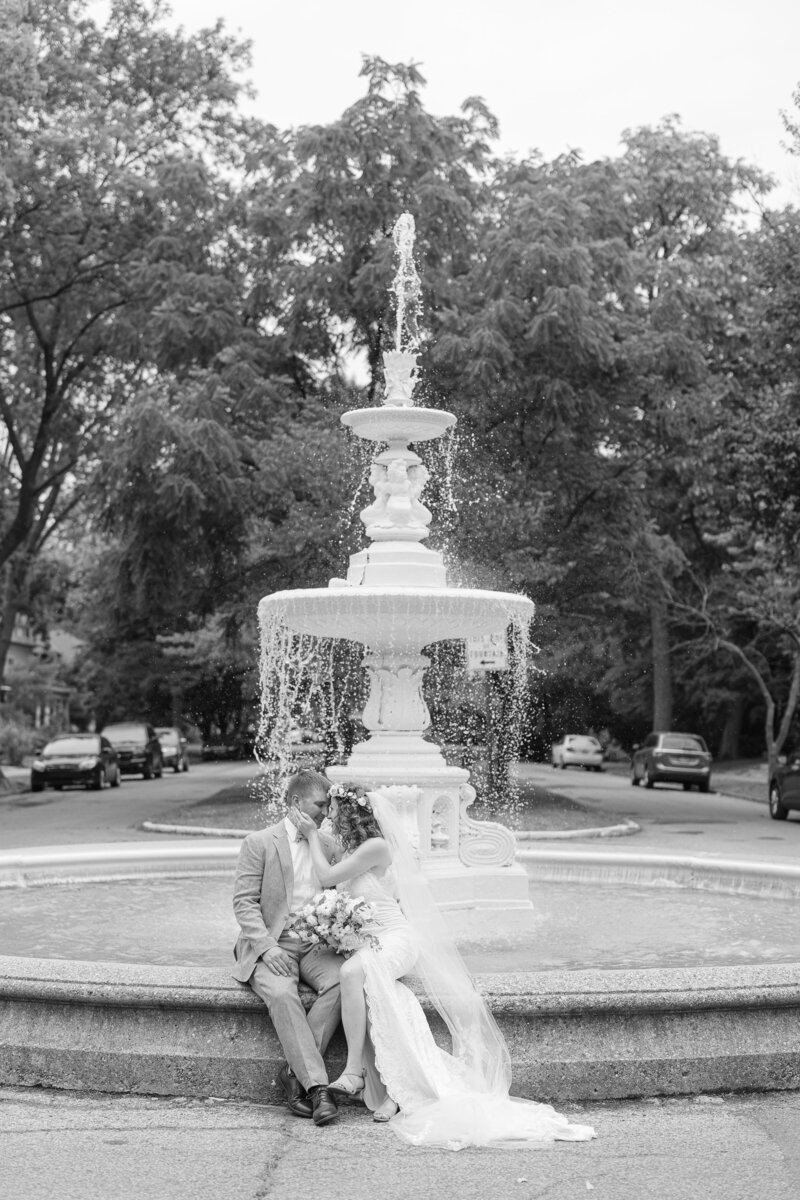 bride and groom kissing in front of the fountain