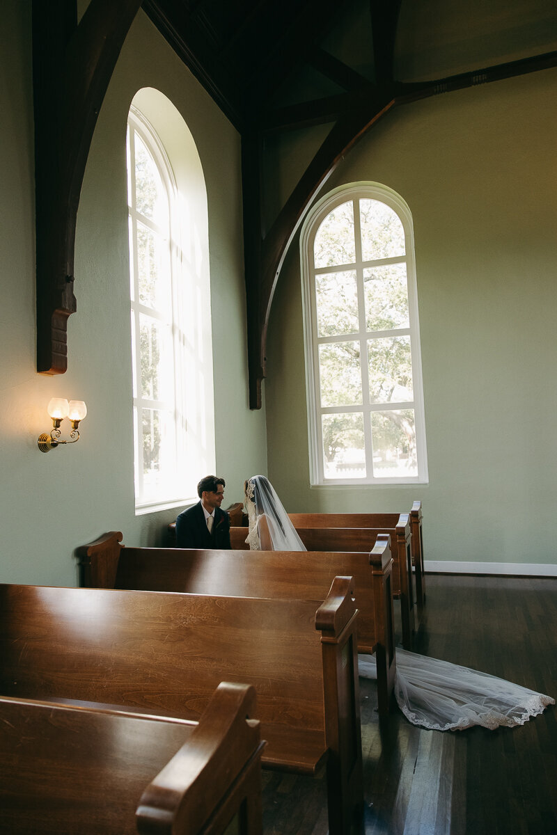 bride and groom sitting in a church pew