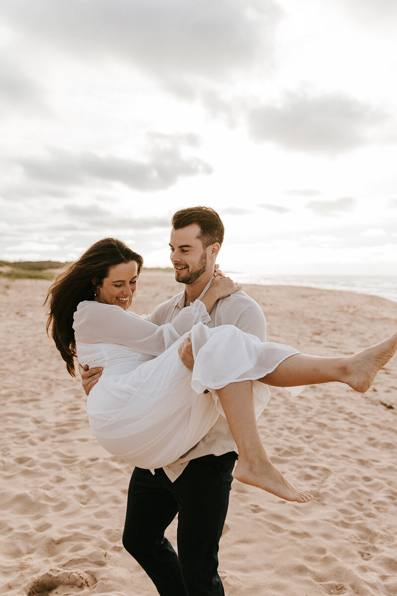 couple playfully posing on beach in prince edward island for lifestyle session
