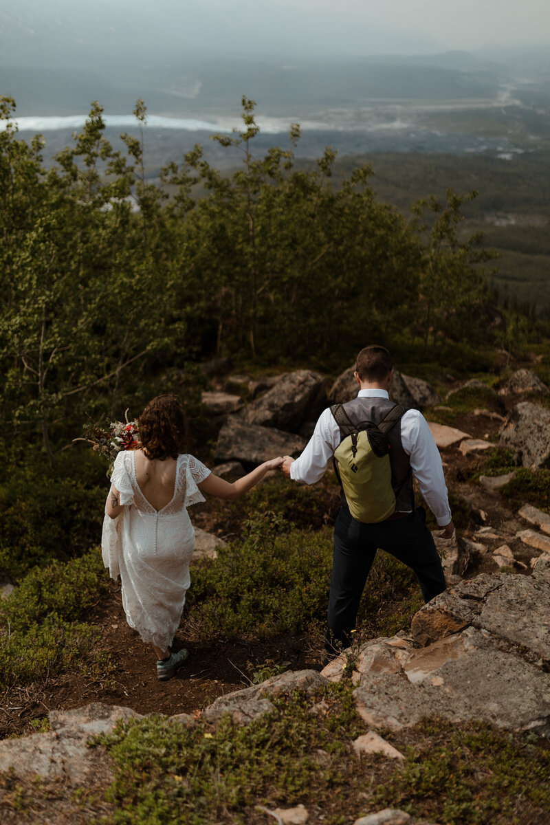 bride and groom on mountains with backpacks