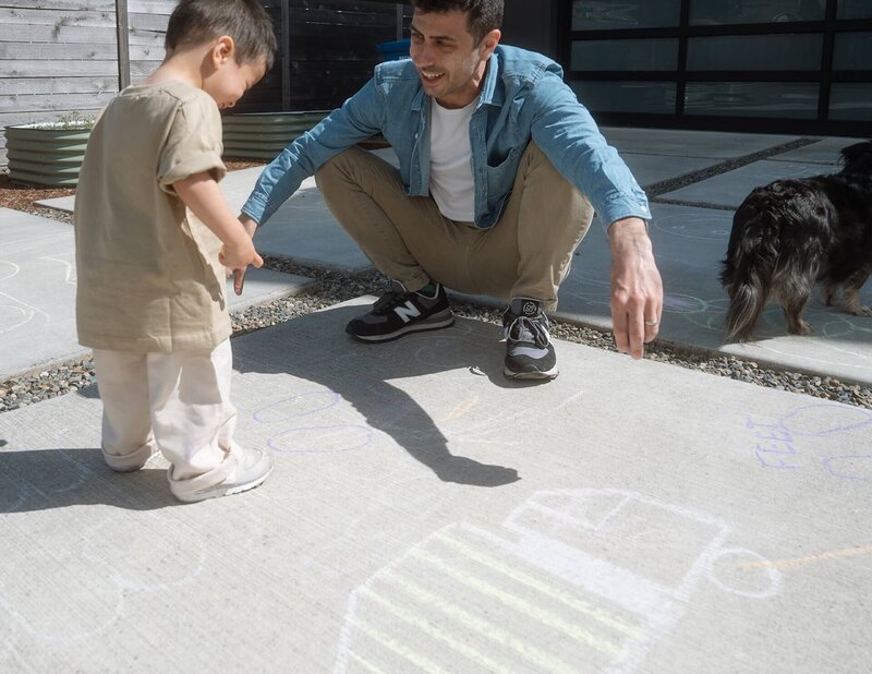 Male doing chalk drawing with son outside on driveway
