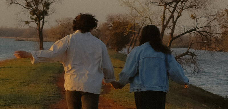 A couple can be seen holding hands and running away from the camera.