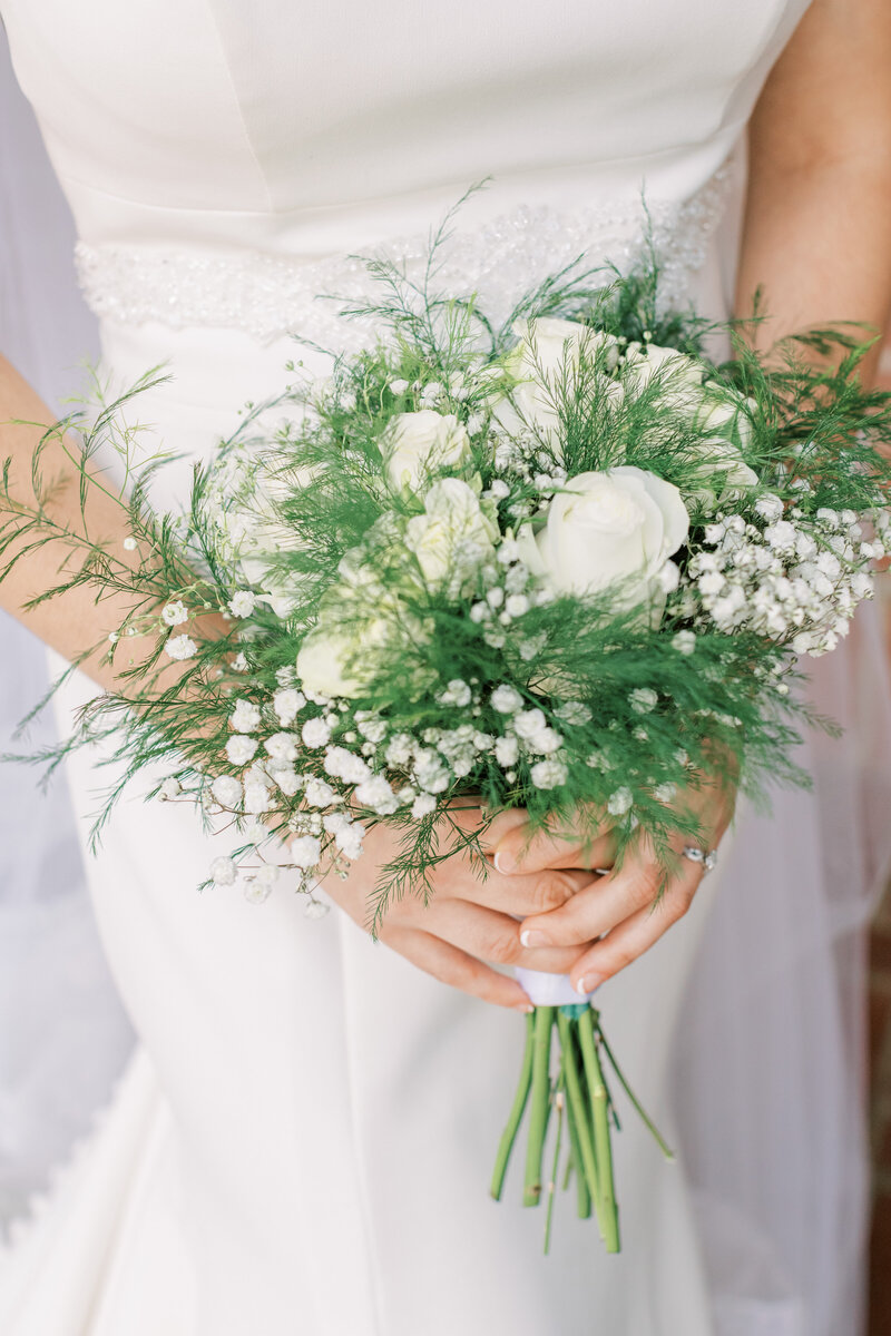 A bride holds her white and green floral mix bouquet.
