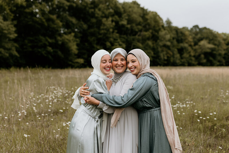A mother and her two daughters embrace in a flower field.