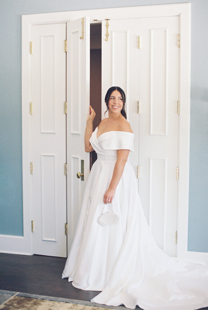 bride looking out window in bridal suite holding purse