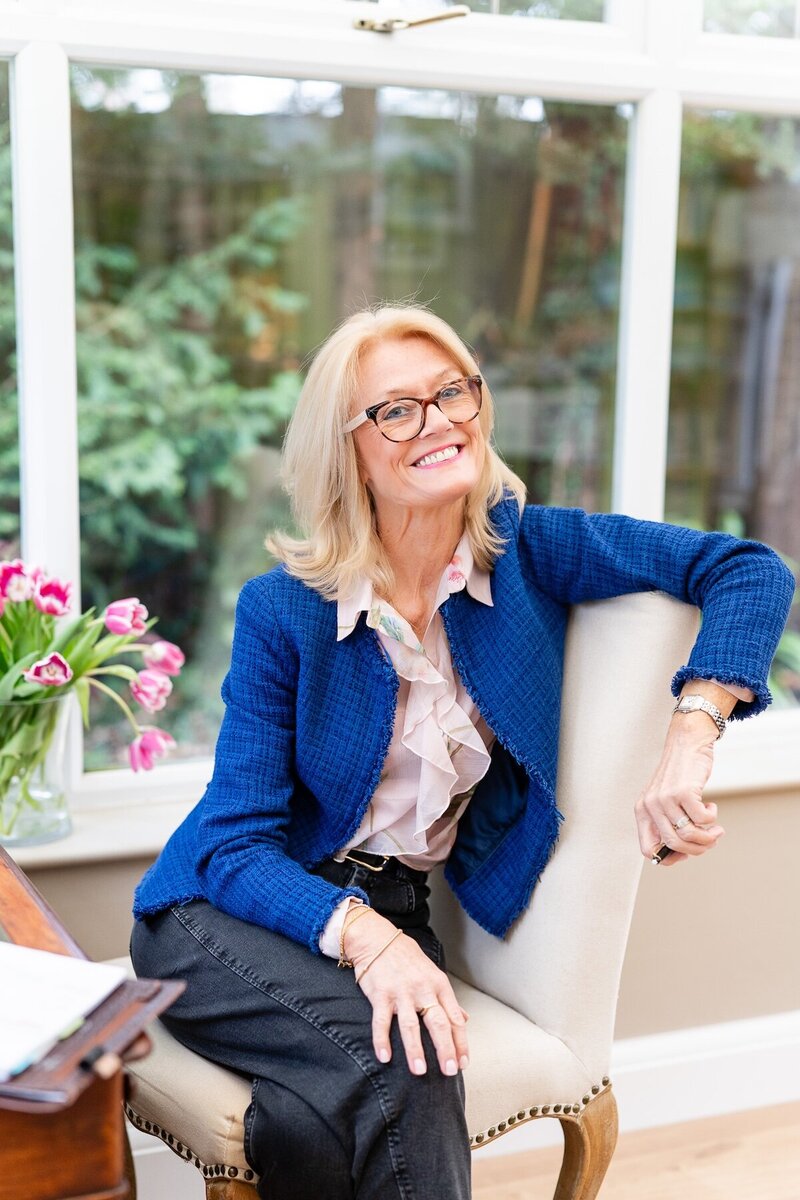 woman in blue blazer sitting on a chair and smiling