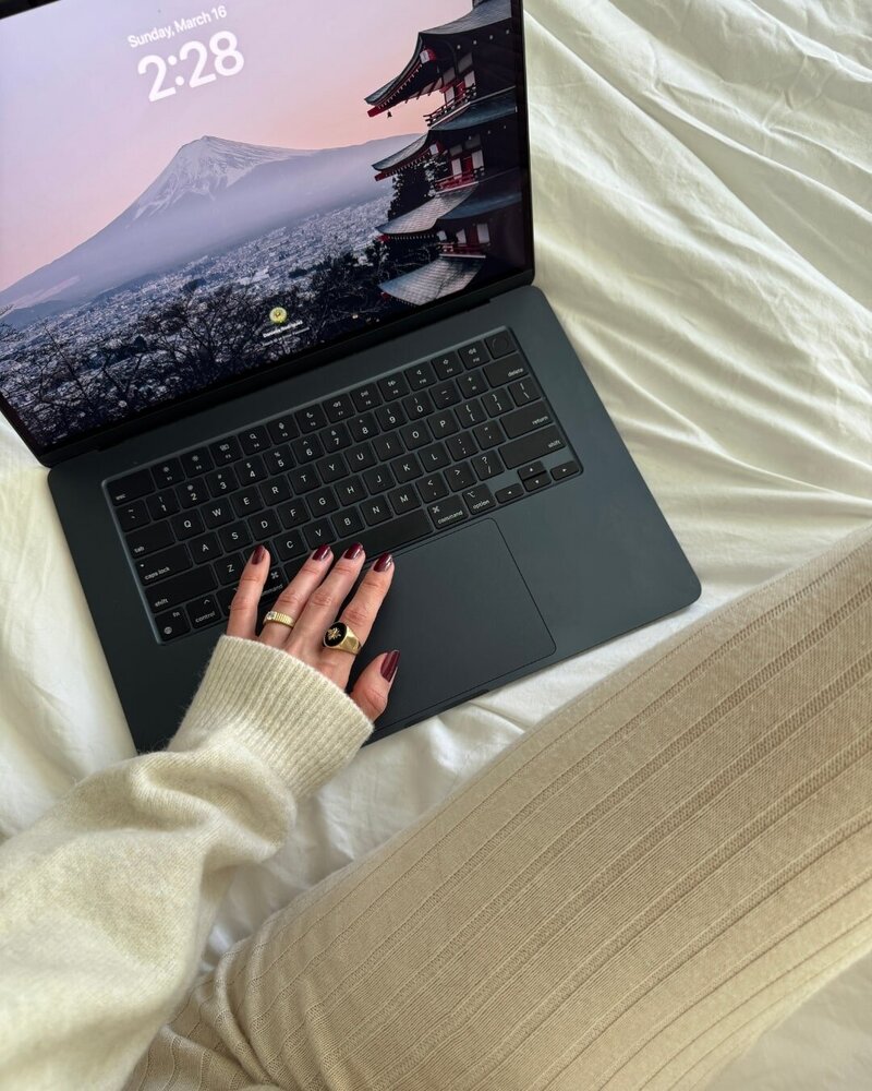 content creator virtual assistant typing on her laptop while sitting in bed