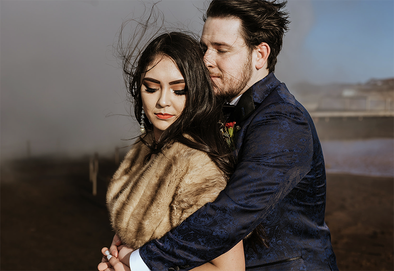 American couple is hugging on a stormy day in a geothermal area in Iceland