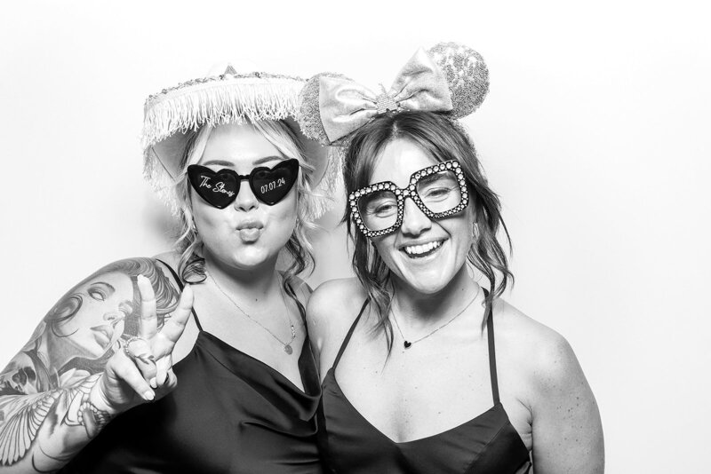 couple posing against a white backdrop with a Kardashian filter, during a corporate event, for Mad Hat Photo Booth Hyde House party entertainment