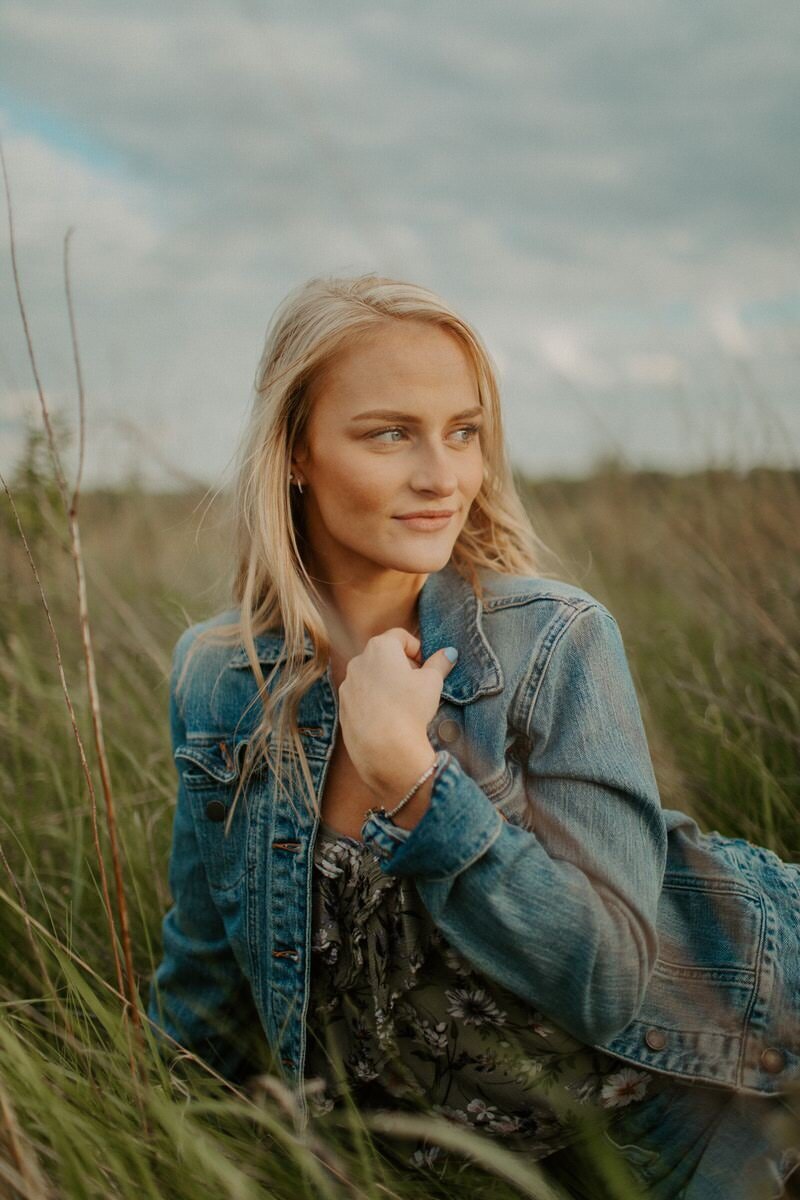 woman wearing a jean jacket while standing in a field
