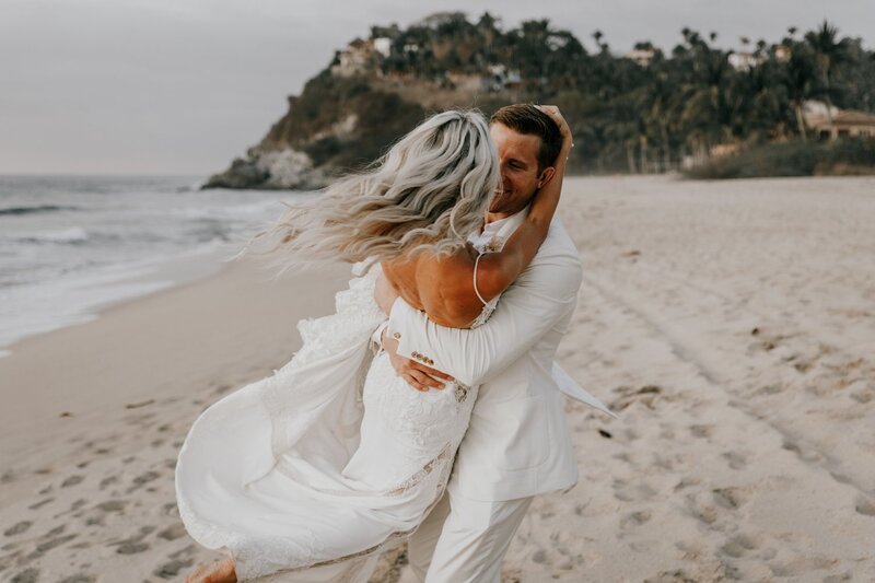 bride and groom dance on beach in san diego after wedding ceremony