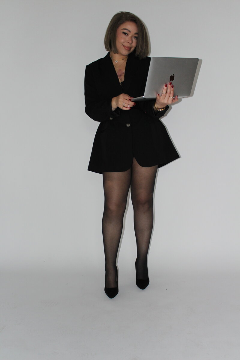 Bri Davis, Founder of Allure Atelier, smiling and holding an open laptop