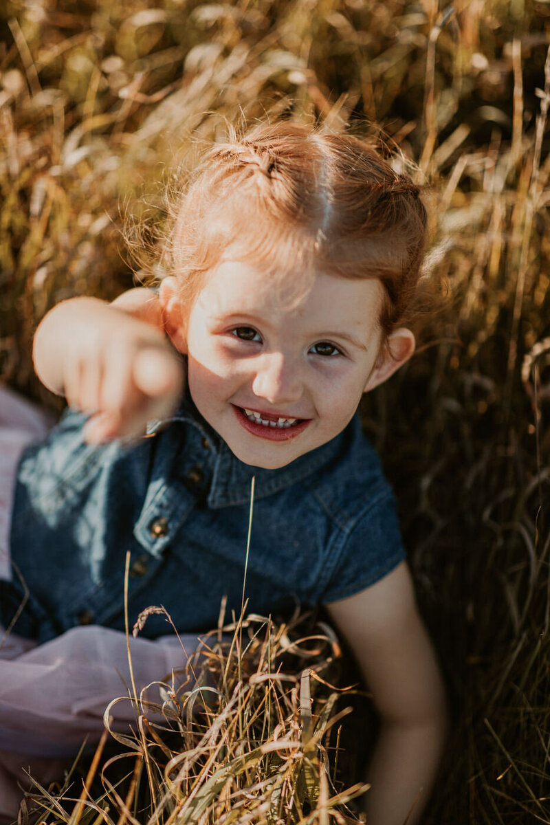 Young girl pointing at the camera having fun at Assiniboine Forest 
