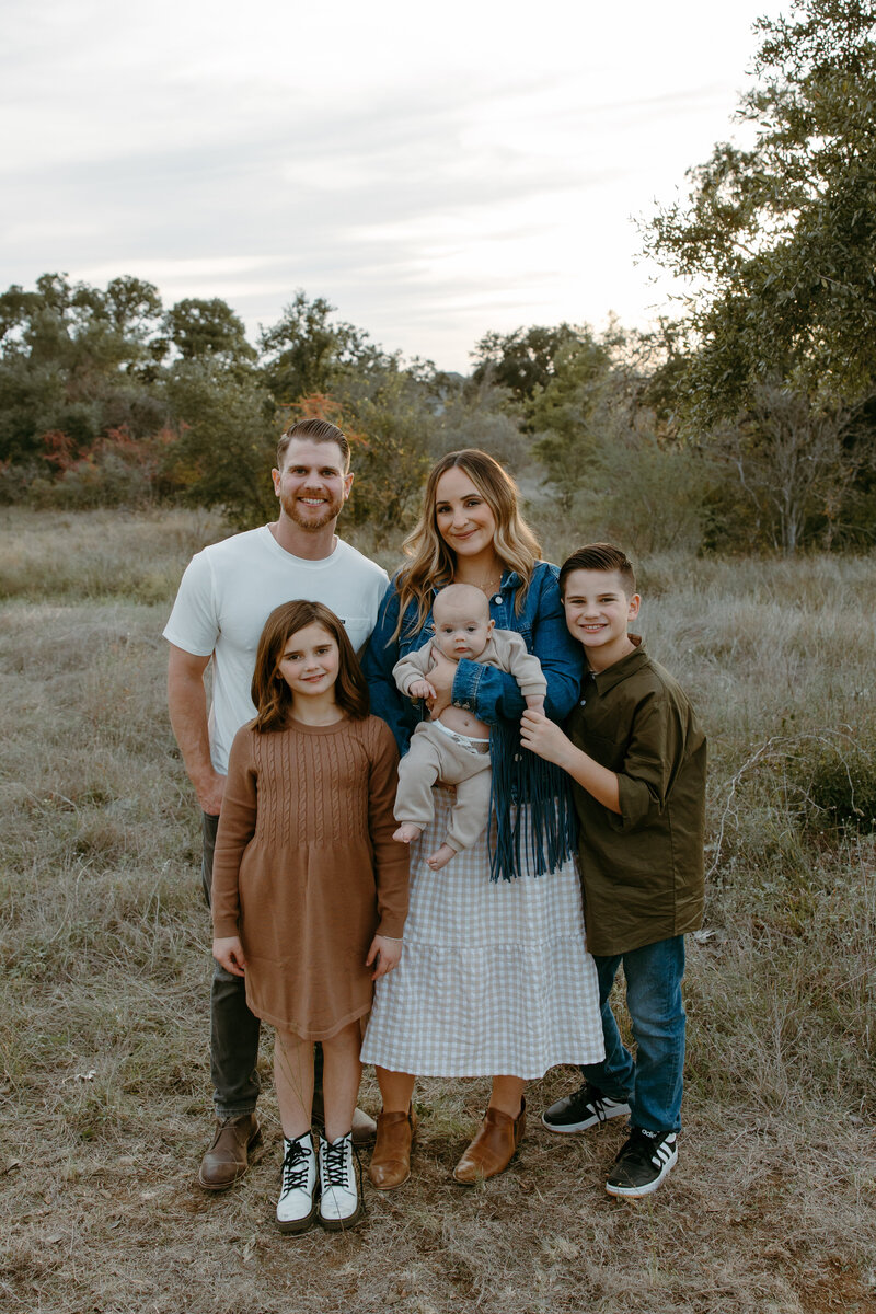 Austin Wedding Photographers Jessie  Schultz posing with their family  in a field