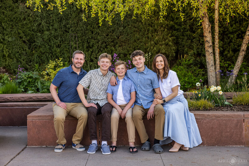 Family sit along a stone wall in the Welcome Garden at Denver Botanic Gardens