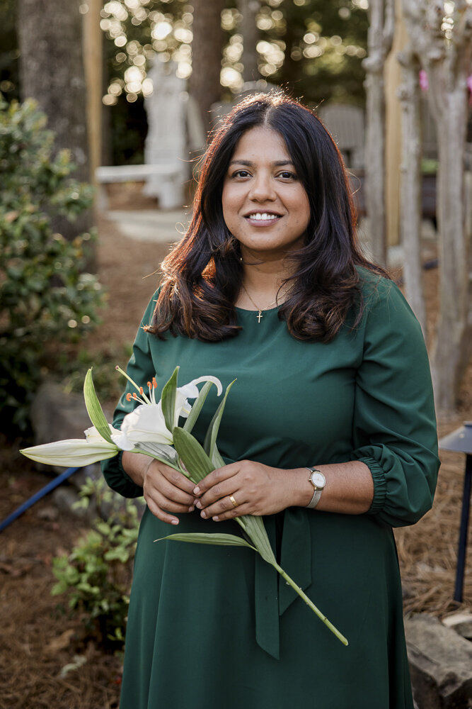 a woman in a green dress holding a white lily flower
