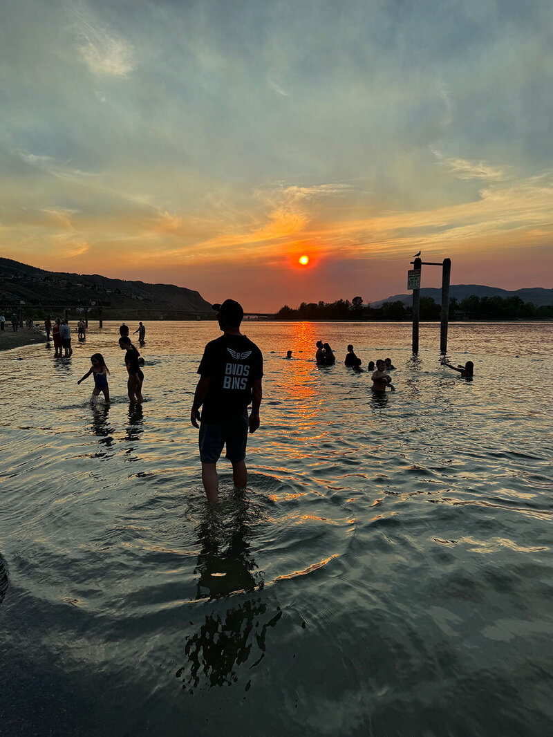 Jonathon-Checcini-in-Buds-Bins-Shirt-in-Shuswap-Lake-with-kids-swimming