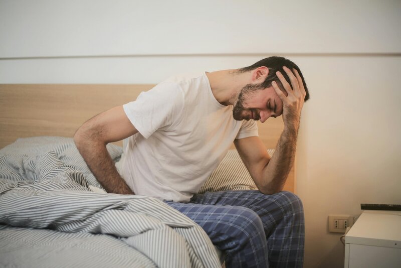 Man sitting on bed looking distressed about high energy bills and poor heating or cooling solutions.