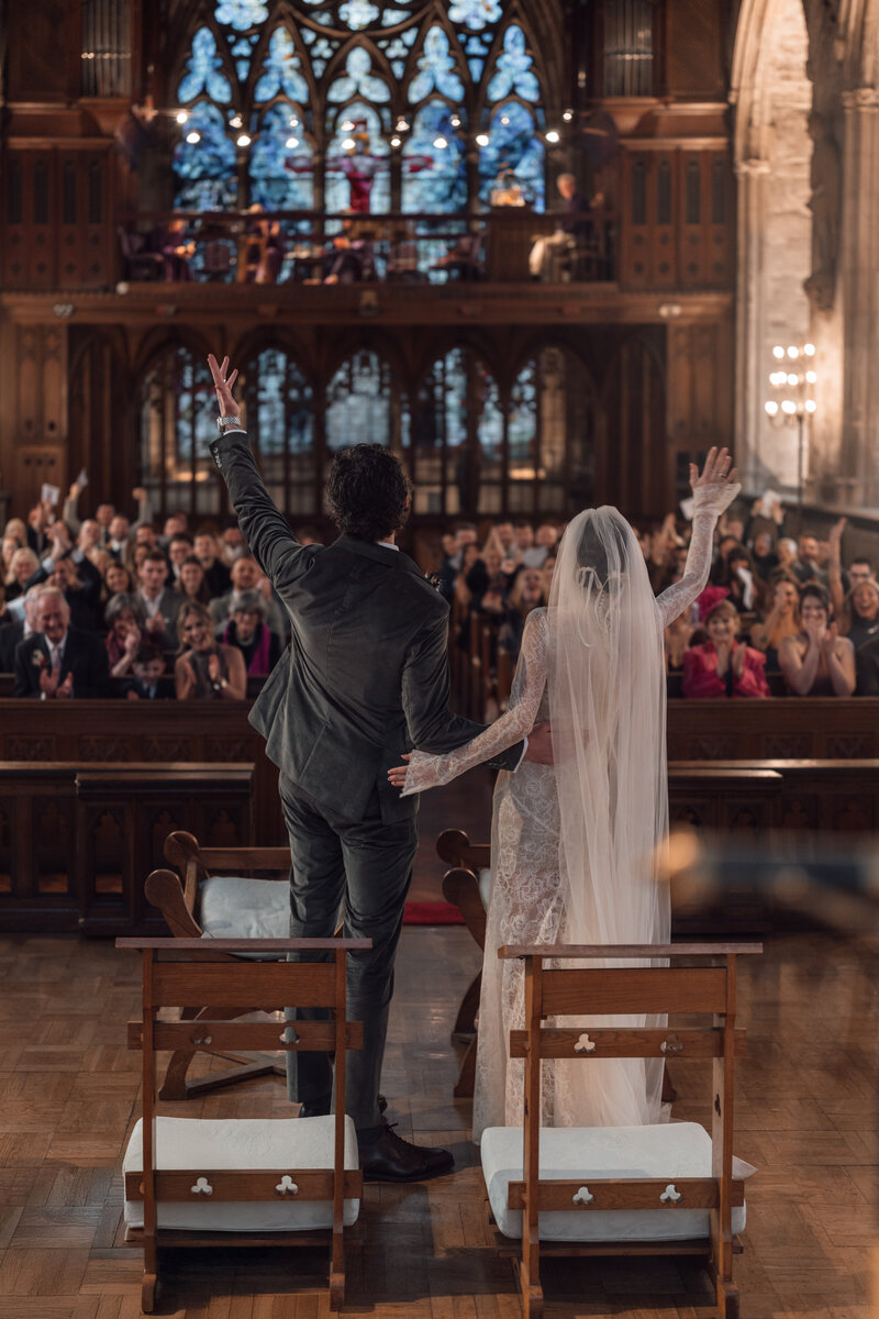 married couple cheer to the church crowd after their first kiss as a newly married couple at st etheldredas chuch central london
