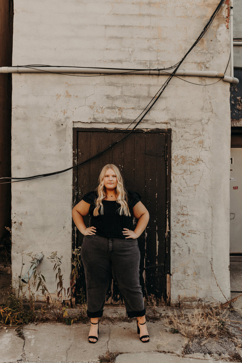 Senior girl standing in front of a black door.