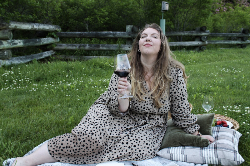 Ashleigh Henry, spiritual life coach and public speaker, captured in Asheville — representing depth, identity reclamation, and soft power for ambitious women while enjoying a glass of malbec near Ralph-Lauren style pillows.