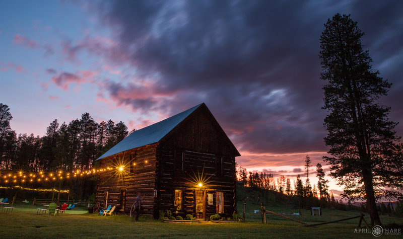 Rustic wood barn lit up at twilight with purple sunset sky in Colorado