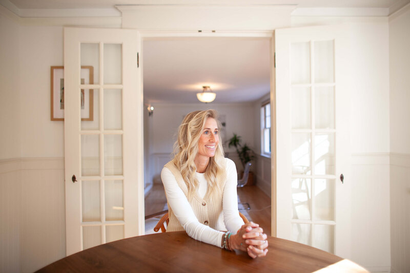 Portland OR realtor and relocation expert, Stephanie, sits with her hands resting on a dining table and smiles. 
