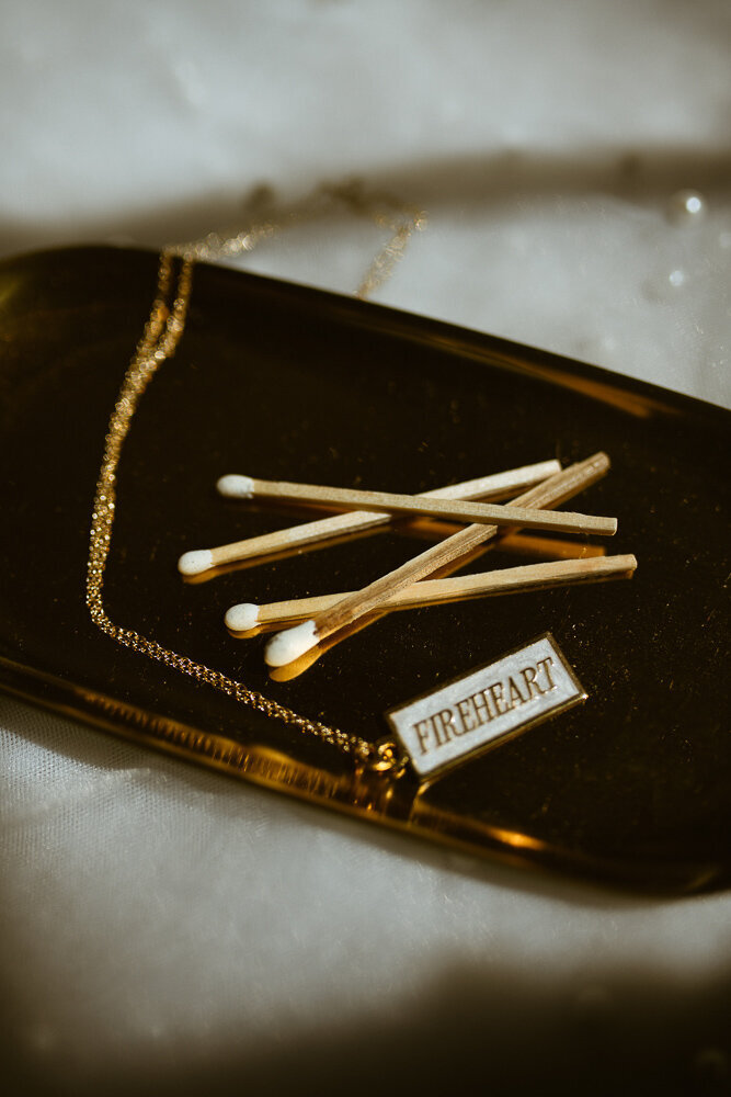 gold necklace on gold platter with matches next to it