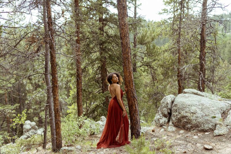 woman with a flower crown and a red dress standing in the forest
