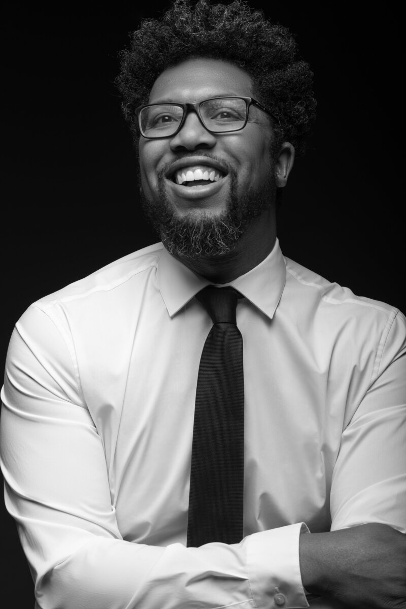 Black and white photo of photographer in shirt and tie laughing