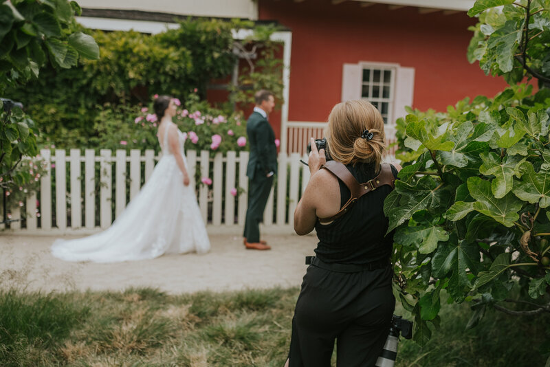 photographer taking photo of bride and groom field