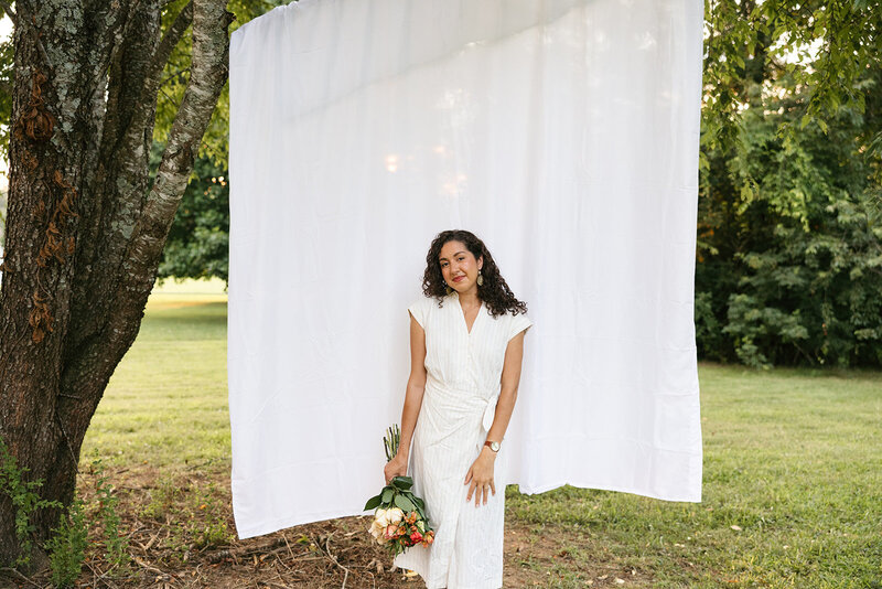 Victoria Barclay, photographer at Through Victoria's Lens, holding flowers in front of a white fabric background