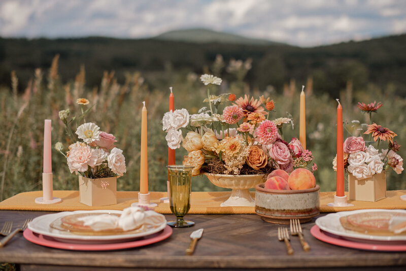 A colorful mountainside sweetheart with candles, flowers, fruit and place settings 