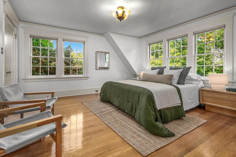 A bedroom, with a bed in front of large windows.